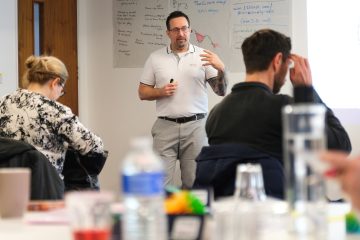 A trainer explaining to a group of people at a training course event