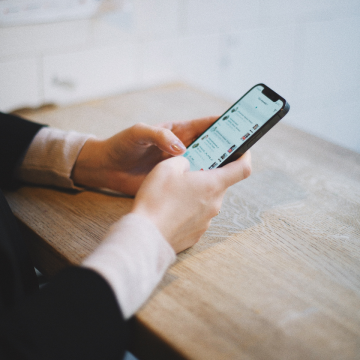 Someone holding a mobile phone in browsing a social media feed